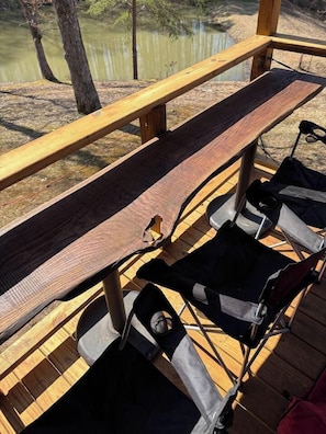 Eine Holzterrasse mit einer Bank und zwei Klappstühlen.