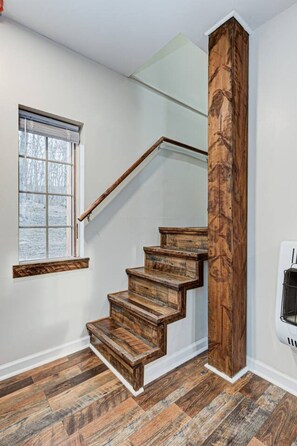 Una escalera de madera con barandilla de cristal que da a una plataforma.