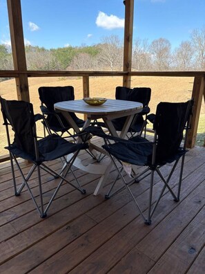 A wooden deck with a round table and four chairs, a bowl on the table, and a view of trees and sky. - The Pond House-Hilltop Views-Private Pond Near RRG (Lee County)