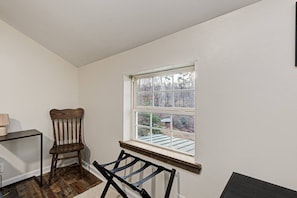 Ein Zimmer mit großem Fenster, einem Holzstuhl, einem kleinen Tisch und einer Heizung.
