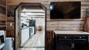 A rustic kitchen with wooden walls, a central island, and a dining area with a round table and chairs.