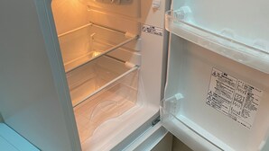 Ένα ψυγείο με ανοιχτή διάταξη, διαφανή πόρτα, διανομέα νερού και ένα μικρό διαμέρισμα καταψύκτη.