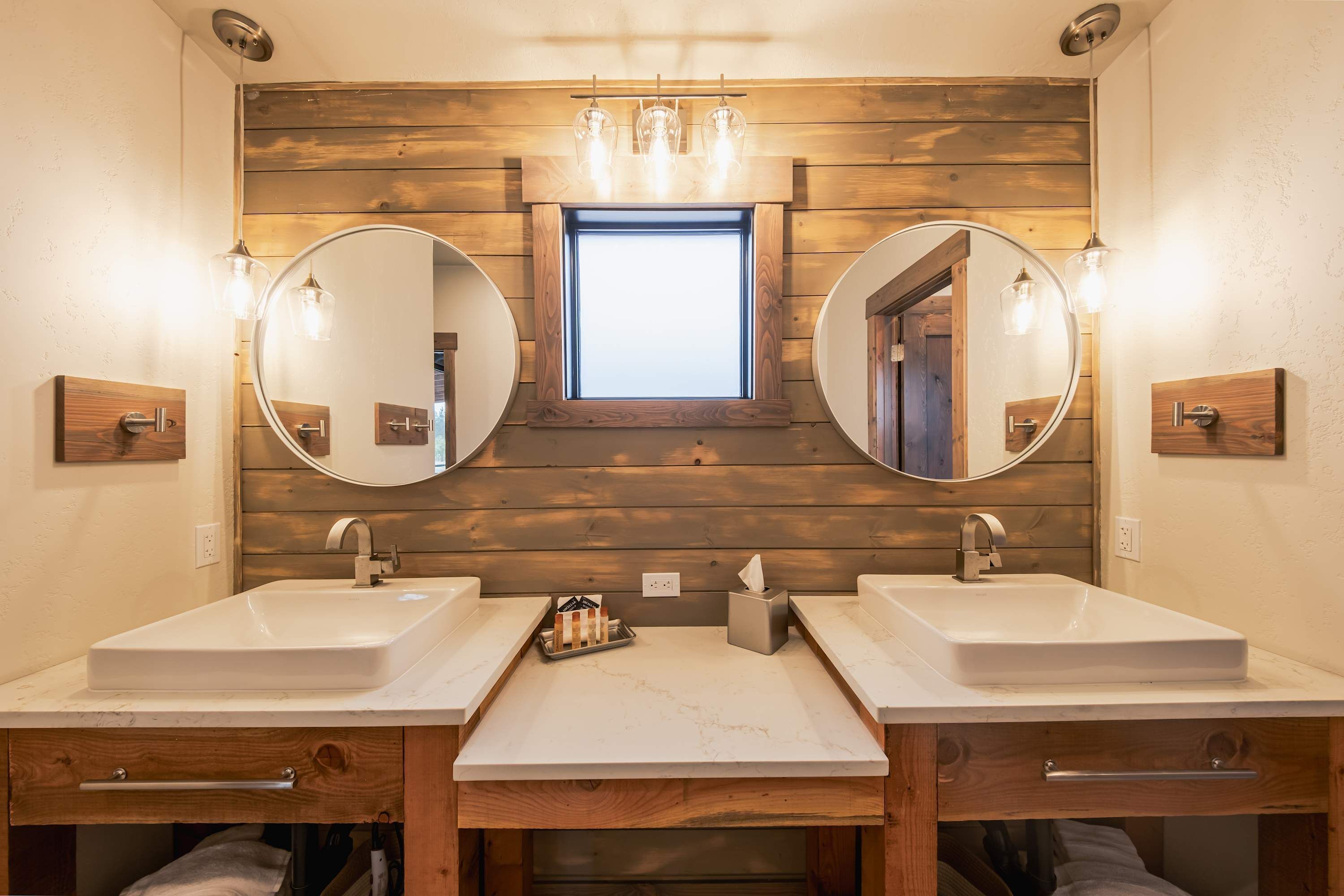A bathroom with two sinks, wooden paneling, and a skylight.