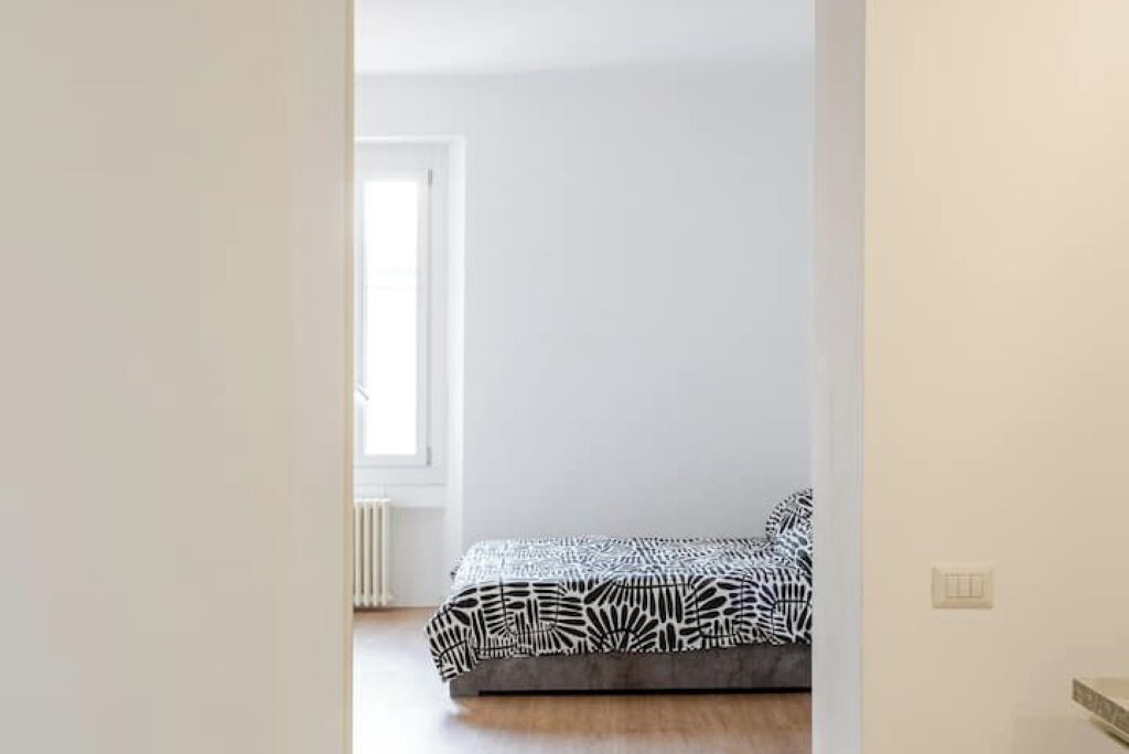 A bedroom with a bed, a window, and a radiator.