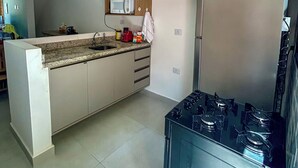 Una cocina moderna con una isla central, microondas integrado, refrigerador de acero inoxidable y estufa a gas.