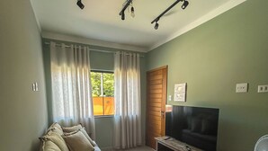 Una sala de estar con un sofá, un televisor y un ventilador.