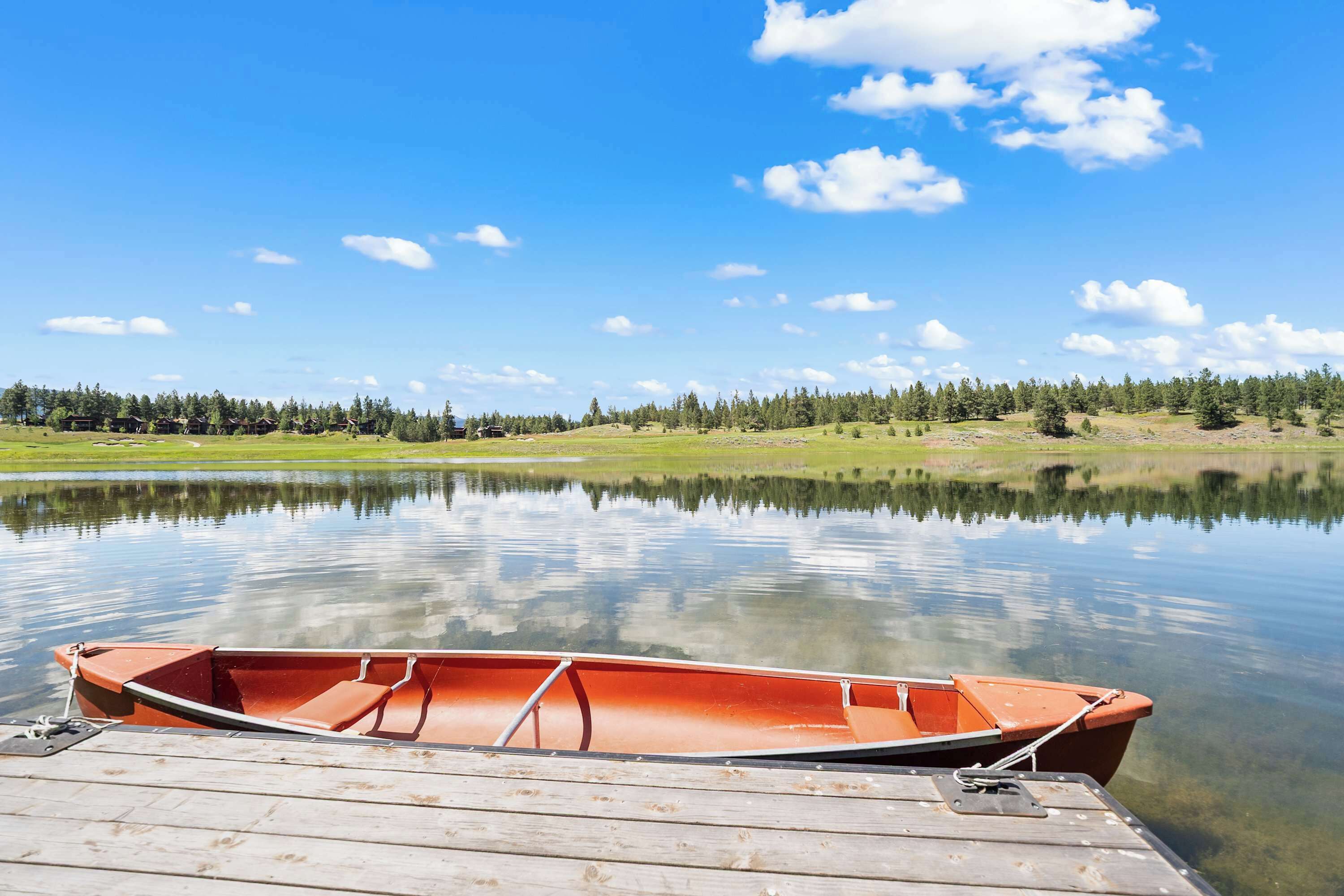 A calm lake with a wooden dock and a small boat.