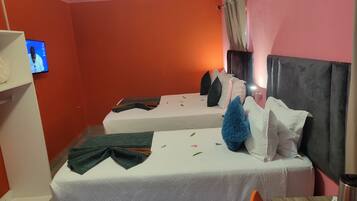 Quarto de hotel com duas camas, televisão na parede e janela com cortinas.