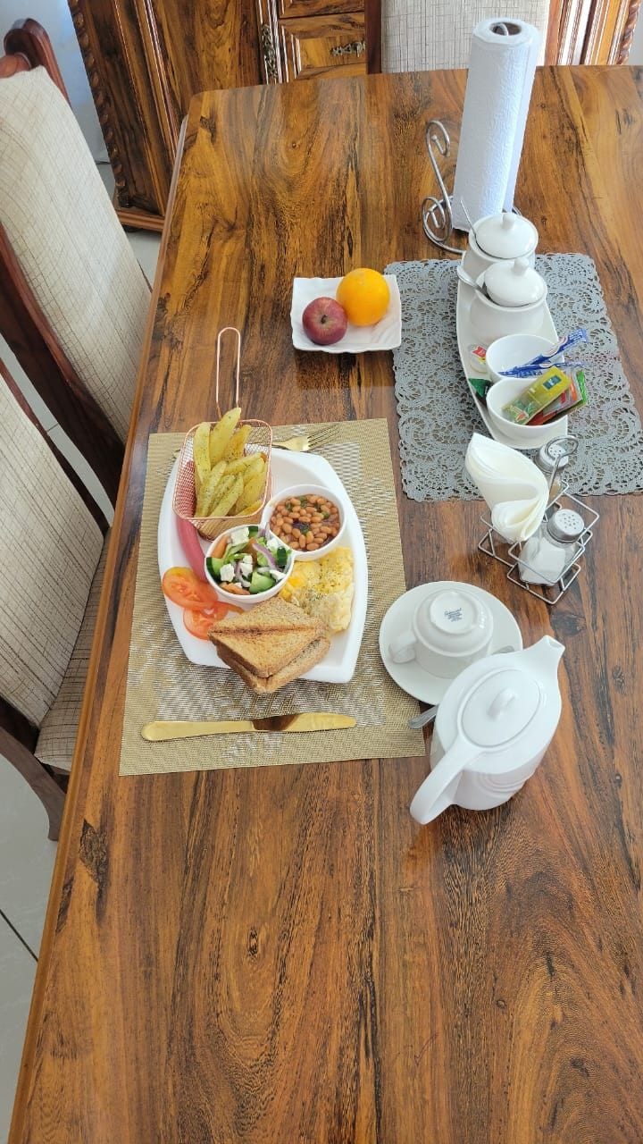 Una mesa de madera con un plato de comida, una tetera y una taza.