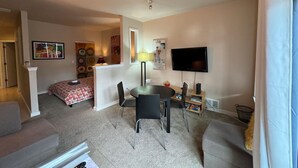 Ein modernes Wohnzimmer mit Essbereich, einem an der Wand montierten Flachbildfernseher und einer gemütlichen Sitzecke.