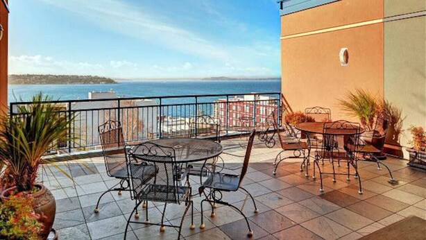 Eine Terrasse mit Tisch und Stühlen, Blick auf das Meer und Kübelpflanzen.