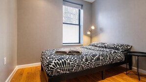 A bedroom with a bed, a window, a floor lamp, and a small table. - Discover the Comfort of Columbia University Area-1 (New York)