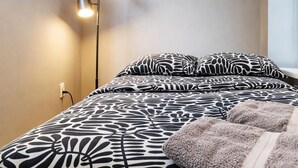 A bedroom with a bed, patterned bedding, a floor lamp, and a window. - Discover the Comfort of Columbia University Area-1 (New York)