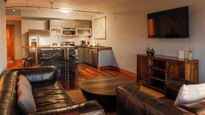 A modern living room with a leather sofa, a coffee table, and a TV mounted on the wall. - 2-Bedroom, 1.5-Bathroom Suite at REAL Watersports (Waves)