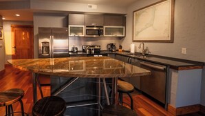 A modern kitchen with a large island, stainless steel appliances, and a bar area. - 2-Bedroom, 1.5-Bathroom Suite at REAL Watersports (Waves)