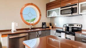 A modern kitchen with stainless steel appliances, a wooden countertop, and a large window with a circular design. - Waterfront 2-Bedroom, 1.5-Bathroom Suite at REAL Watersports (Waves)