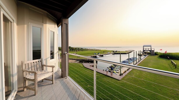 A balcony with a wooden bench, overlooking a marina with boats and a grassy area. - Waterfront 2-Bedroom, 1.5-Bathroom Suite at REAL Watersports (Waves)