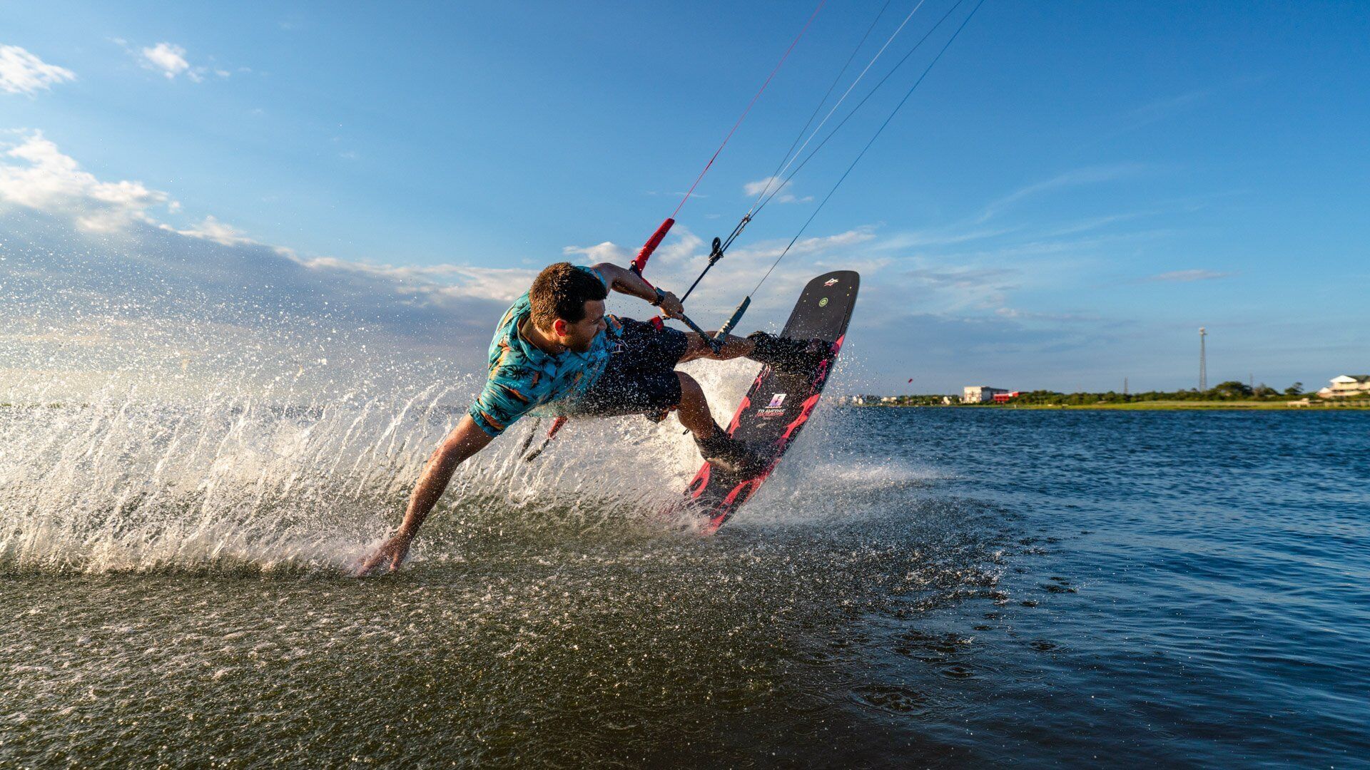 A person windsurfing on a body of water with a clear sky in the background.