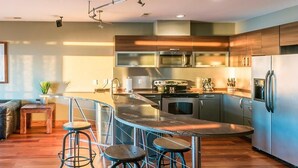 A modern kitchen with a central island, stainless steel appliances, and a bar stool area. - Waterfront 3-Bedroom, 2.5-Bathroom Penthouse Suite at REAL Watersports (Waves)