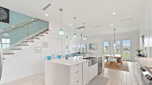 Una cocina moderna con una isla central, armarios blancos y sillas azules.
