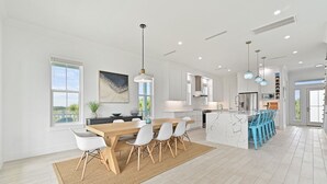 Una cocina amplia con una isla central, armarios blancos e iluminación colgante.