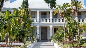 A white colonial-style building with a symmetrical facade, large windows, and a central entrance. - Hillcrest Boutique Hotel (Town of St. George)