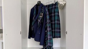 Ein weißer Kleiderschrank mit drei Einlegeböden, auf denen verschiedene Gegenstände liegen.