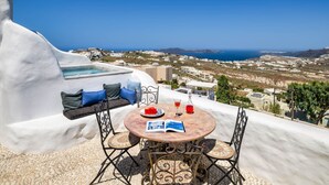 Une terrasse avec une table ronde, des chaises et un canapé avec des coussins.