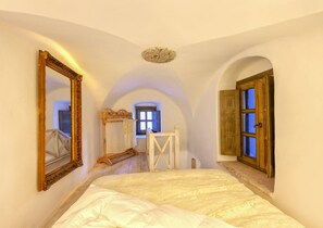 A bedroom with a large bed, a wooden ladder, a window with blue light, and a door with wooden shutters. - Villa Castelli - Five Bedroom Villa, Sleeps 10 (Pirgos Kallistis)
