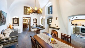 Un vaste espace de vie doté d’un haut plafond, d’une table à manger et d’un coin cuisine visible à travers une arche.