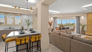 Eine moderne Wohnung mit Küche, Essbereich und Wohnzimmer. Sie verfügt über ein großes Fenster, eine Couch und einen Esstisch mit Stühlen.