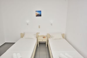 A twin room with two beds, a small bedside table, a nightstand, and a single wall-mounted picture.