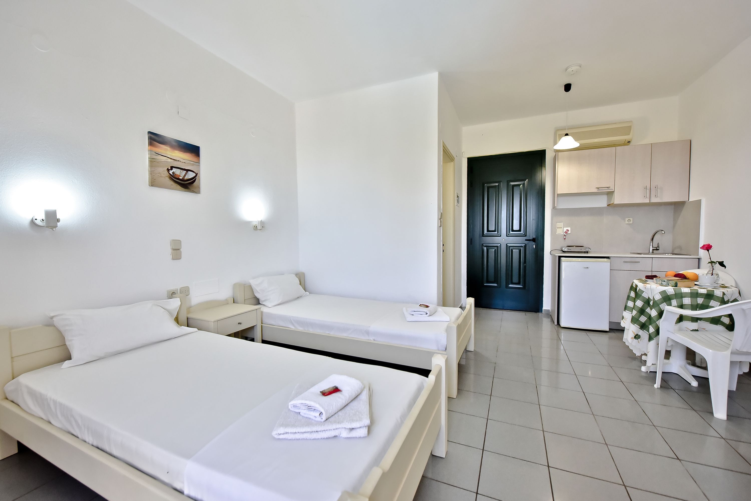 Une chambre d’hôtel avec deux lits, une petite kitchenette et un coin repas comprenant une table et des chaises.