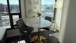 A modern dining area with a round table, two chairs, a vase with a flower, and a decorative wall piece. - Stylish King Suite • Tysons Corner Mall Access • Metro Nearby (Tysons)