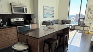 A modern kitchen with a central island, stainless steel appliances, and a view of the city through large windows. - Stylish King Suite • Tysons Corner Mall Access • Metro Nearby (Tysons)