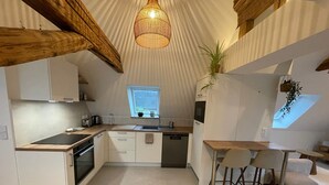 A modern kitchen with a central island, built-in appliances, and a small dining area with stools. - La Girouette - in the heart of a farmhouse (Mittelhausbergen)