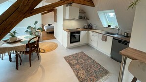 A modern kitchen with white cabinets, a wooden dining table, and a large window. - La Girouette - in the heart of a farmhouse (Mittelhausbergen)