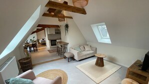 A spacious loft with a high ceiling, exposed wooden beams, a cozy seating area with a sofa and armchairs, a dining table, and a kitchen in the background. - La Girouette - in the heart of a farmhouse (Mittelhausbergen)