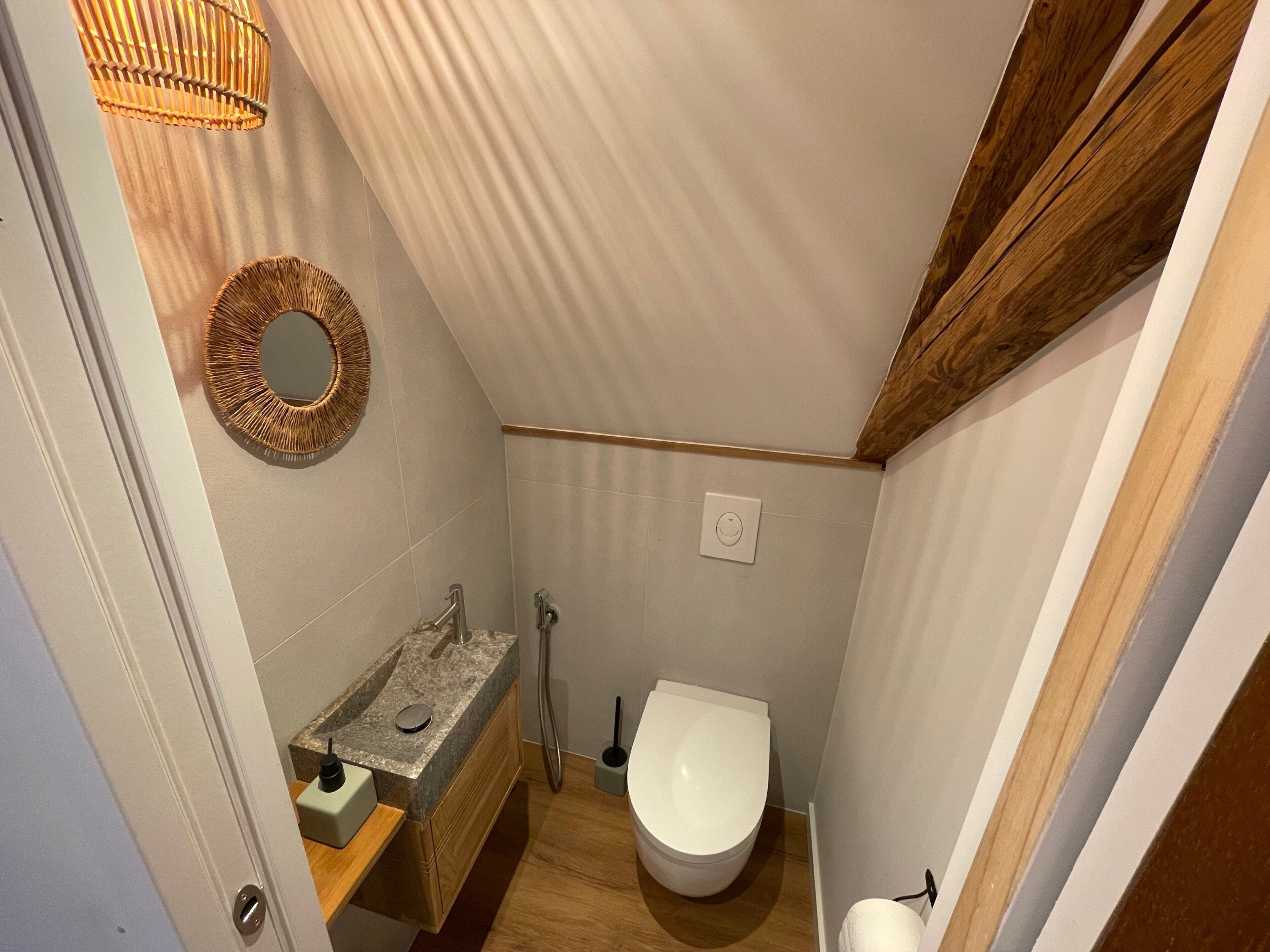 A compact bathroom with a vanity, toilet, and a wall-mounted mirror.