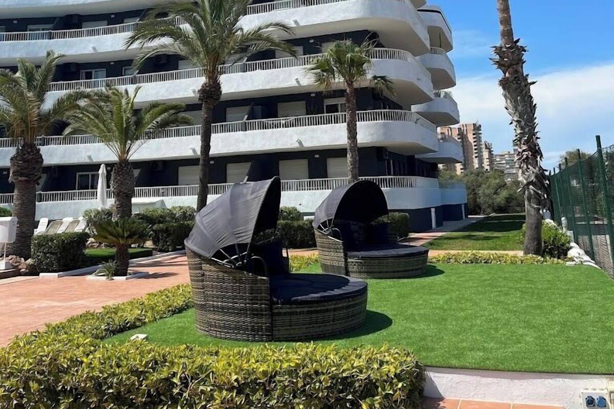 Un hotel de varios pisos con balcones, palmeras y un césped bien cuidado.