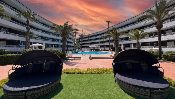 Ein Hotel mit Pool, Außenbereich und Palmen.