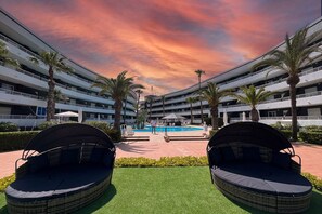 Un hotel con piscina, zona de estar al aire libre y palmeras.