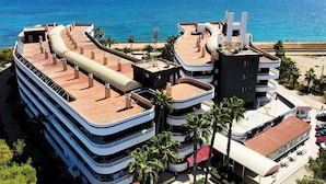 Ein mehrstöckiges Hotel mit Balkonen mit Blick auf den Ozean, einem Poolbereich und einer Strandansicht.