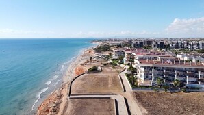 Eine Küstenlandschaft mit Strand, Wohnhäusern und blauem Himmel.
