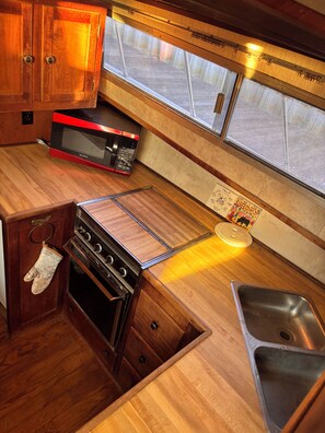 Una cocina compacta con muebles de madera, microondas, horno y lavabo.
