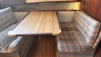 Un intérieur de camping-car compact avec une table en bois et des sièges à motifs écossais.