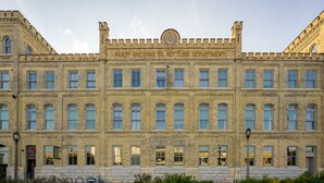 Un edificio grande e histórico con fachada simétrica, numerosas ventanas y un reloj central.