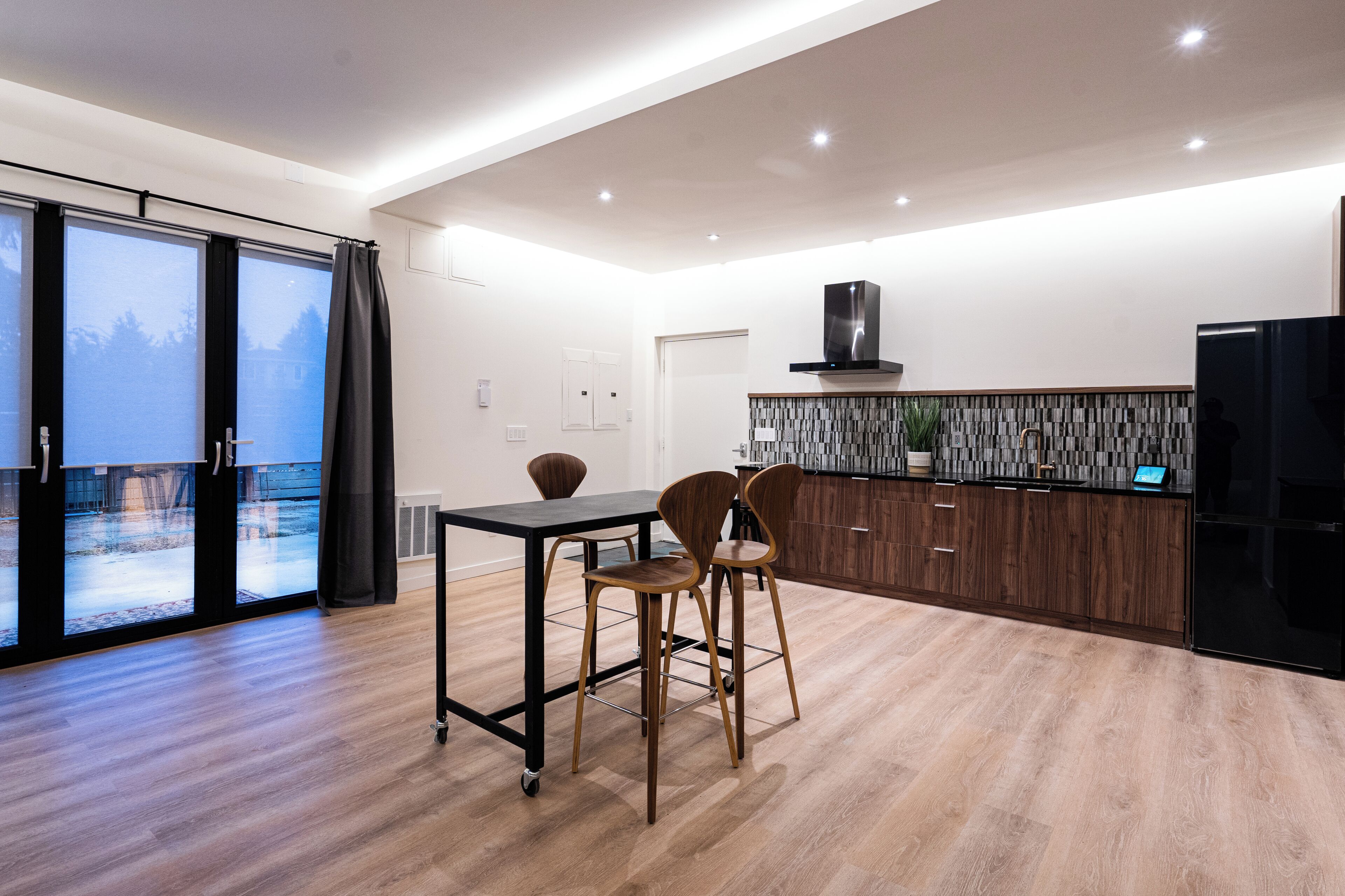 Una cocina moderna con comedor, ventanas amplias y vistas a un paisaje nevado.