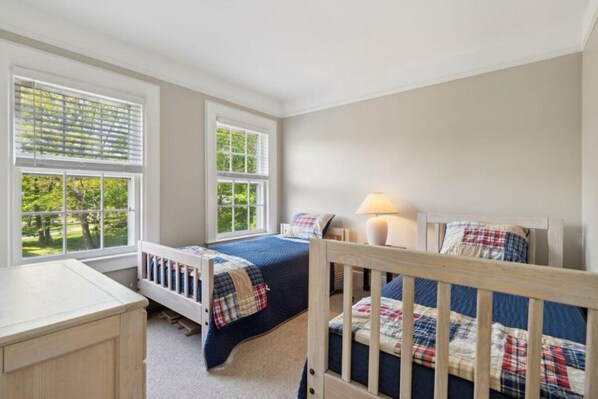 A bedroom with two beds, a desk, and large windows. - A Spacious and Charming Island Townhome (Portland)