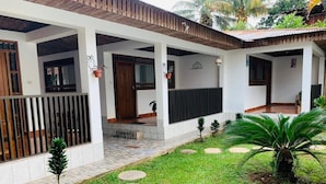 A covered outdoor area with a tiled floor, a small garden with stepping stones, and a palm tree. - Puerto Azul  (Sauce)